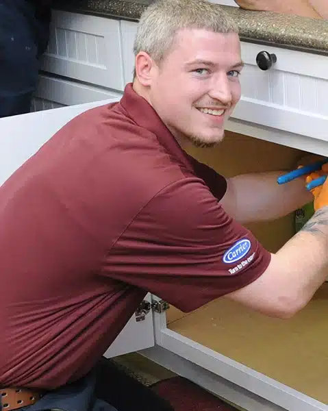 Austin Campbell fixing a leak under a kitchen sink.