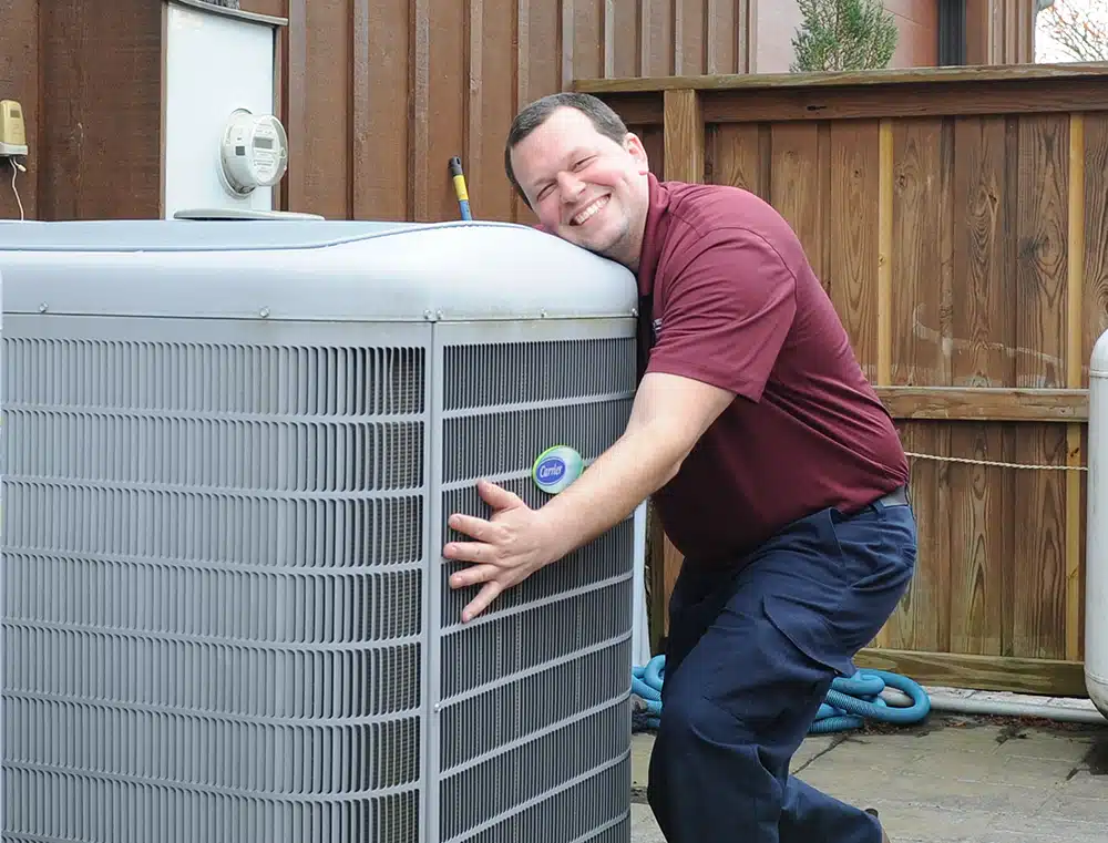 Appleton Campbell electrician hugging AC unit outside in Warrenton, VA.