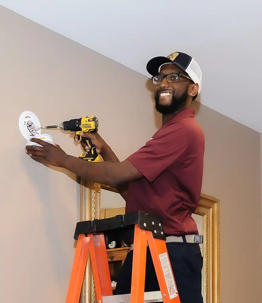 Technician installing smoke detector in residential home in Warrenton, VA.